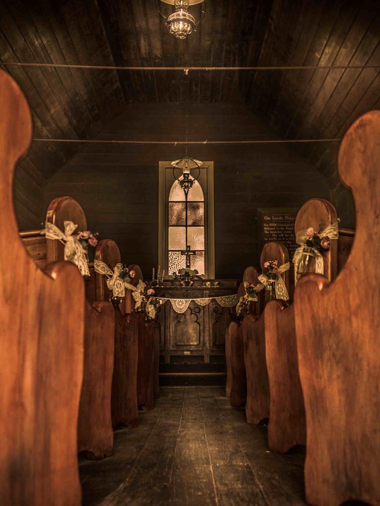 Blick entlang des leeren Gangs einer hölzernen Siedlerkirche zum Altar.