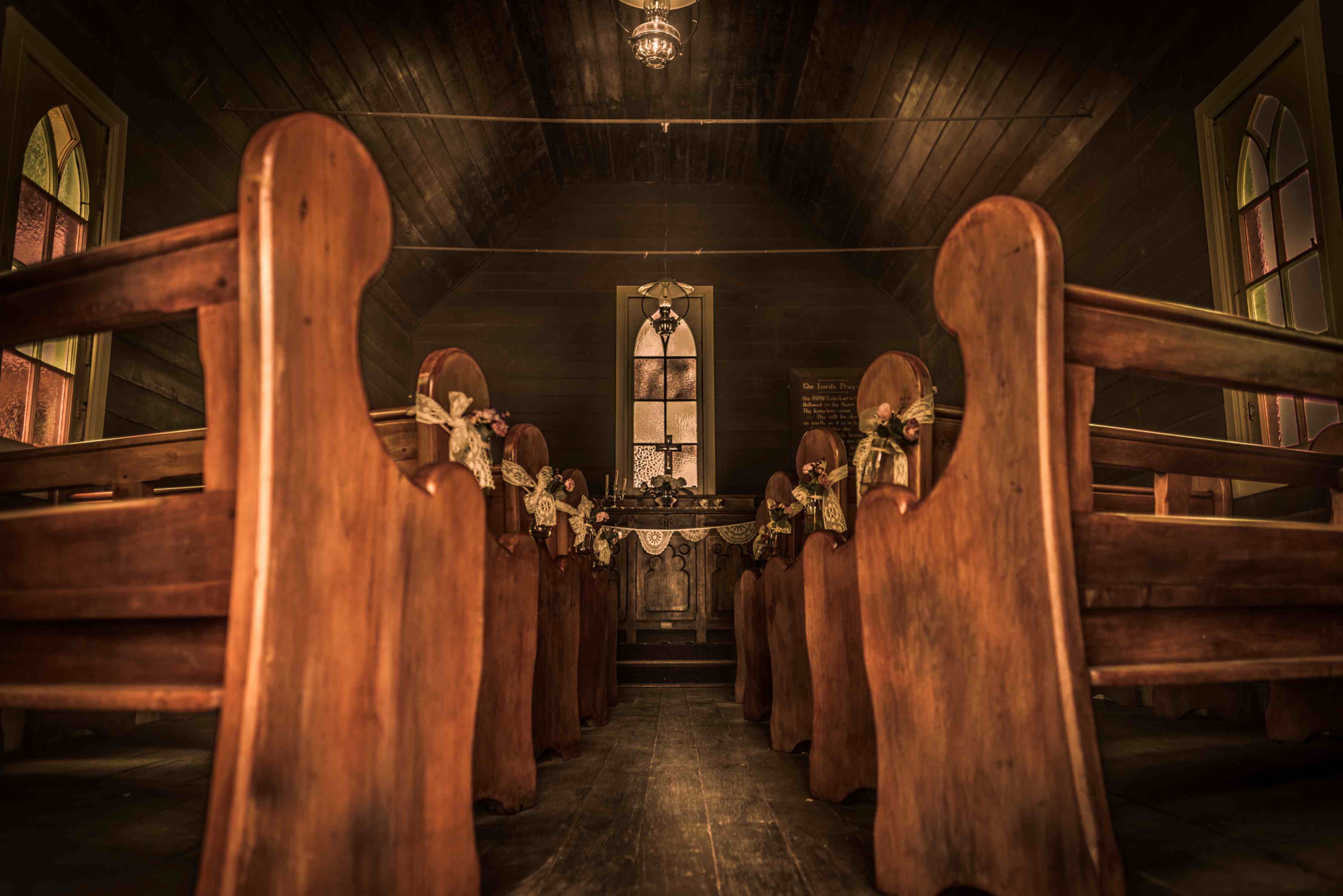 Blick entlang des leeren Gangs einer hölzernen Siedlerkirche zum Altar.
