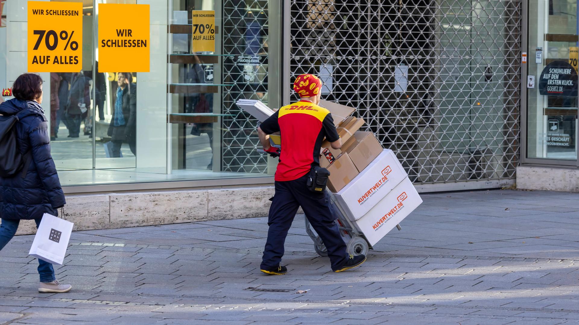 Ein Paketbote bugsiert viele Pakete auf einer Sackkarre durch die Innenstadt von Stuttgart. Ein Paketbote bugsiert viele Pakete auf einer Sackkarre durch die Innenstadt von Stuttgart.