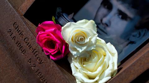 Blumen und eine Kerze liegen vor einem Foto von Chris Gueffroy.