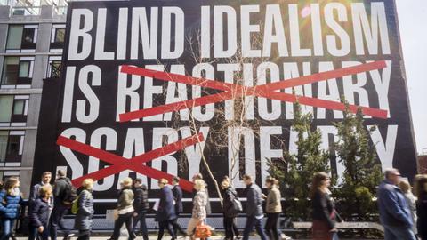 "BLIND IDEALISM IS REACTIONARY SCARY DEADLY", steht auf einem Plakat, das in New York hängt. Die New Yorker Künstlerin beruft sich auf ein Zitat des Psychiaters und Aktivisten Frantz Fanon. 