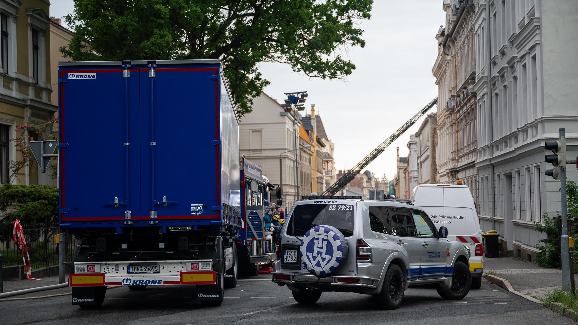 Fahrzeuge des THW steht in einer Straße mit Altbauten. 