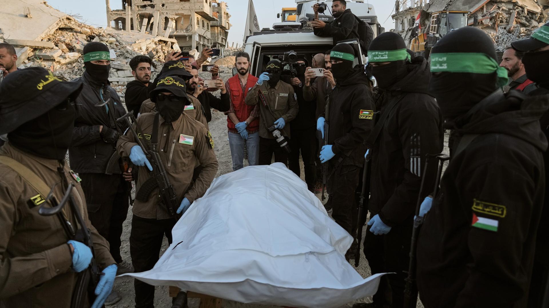 Beit Lahiya: Maskierte Kämpfer des Islamischen Dschihad und der Hamas übergeben im nördlichen Gazastreifen einen Leichensack an das Rote Kreuz zur Übergabe an israelische Behörden.