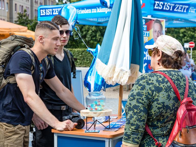 Mitgleider der Jungen Alternative, der Jugendorganisation der AfD, sprechen auf einer Wahlkampfveranstaltung der AfD Brandenburg in Cottbus mit einer Besucherin der Veranstaltung.