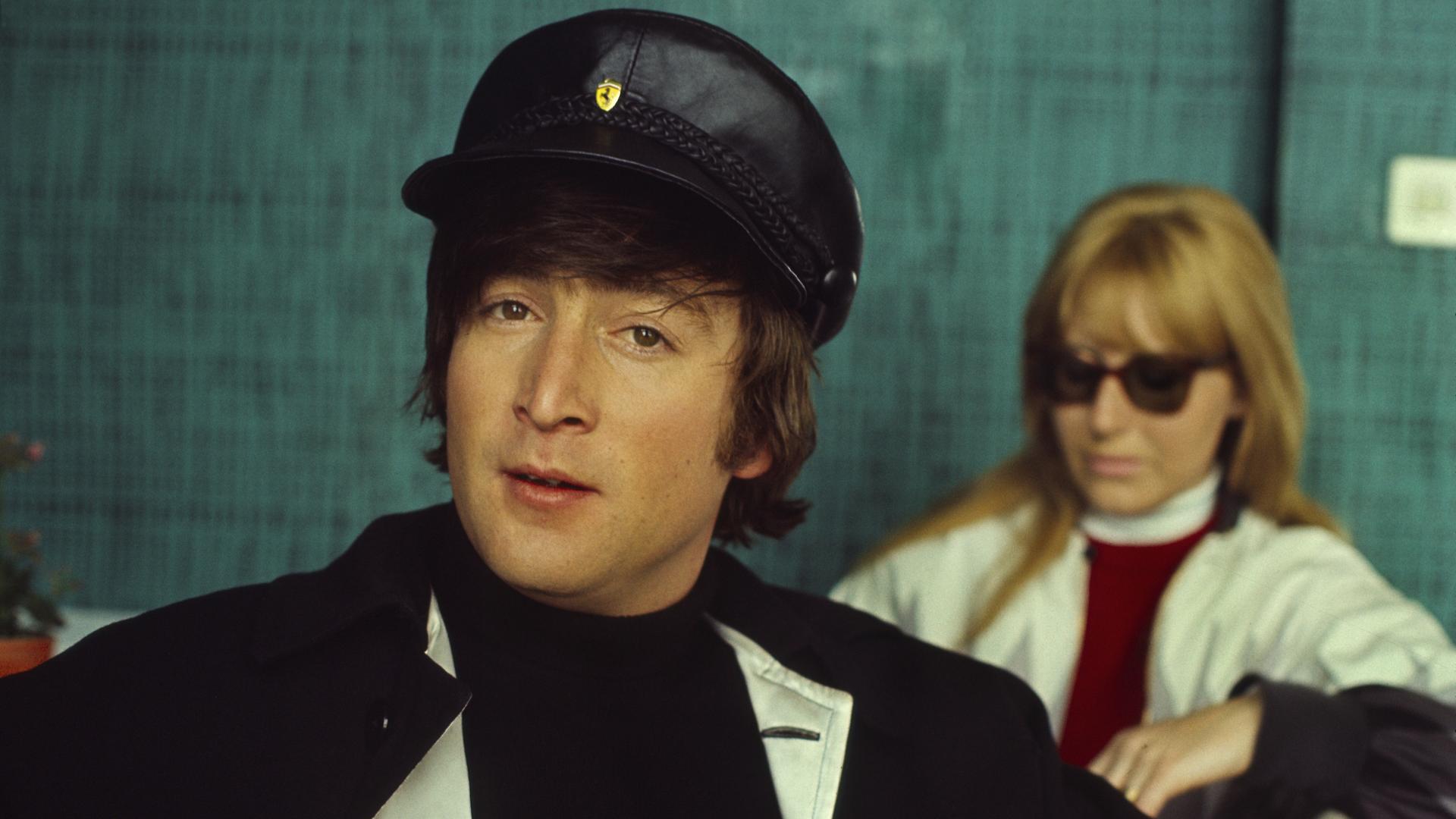 Der britische Musiker und Beatle John Lennon mit seiner ersten Ehefrau Cynthia Powell im Hintergrund aufgenommen circa 1964. Der britische Musiker und Beatle John Lennon mit seiner ersten Ehefrau Cynthia Powell im Hintergrund aufgenommen circa 1964.