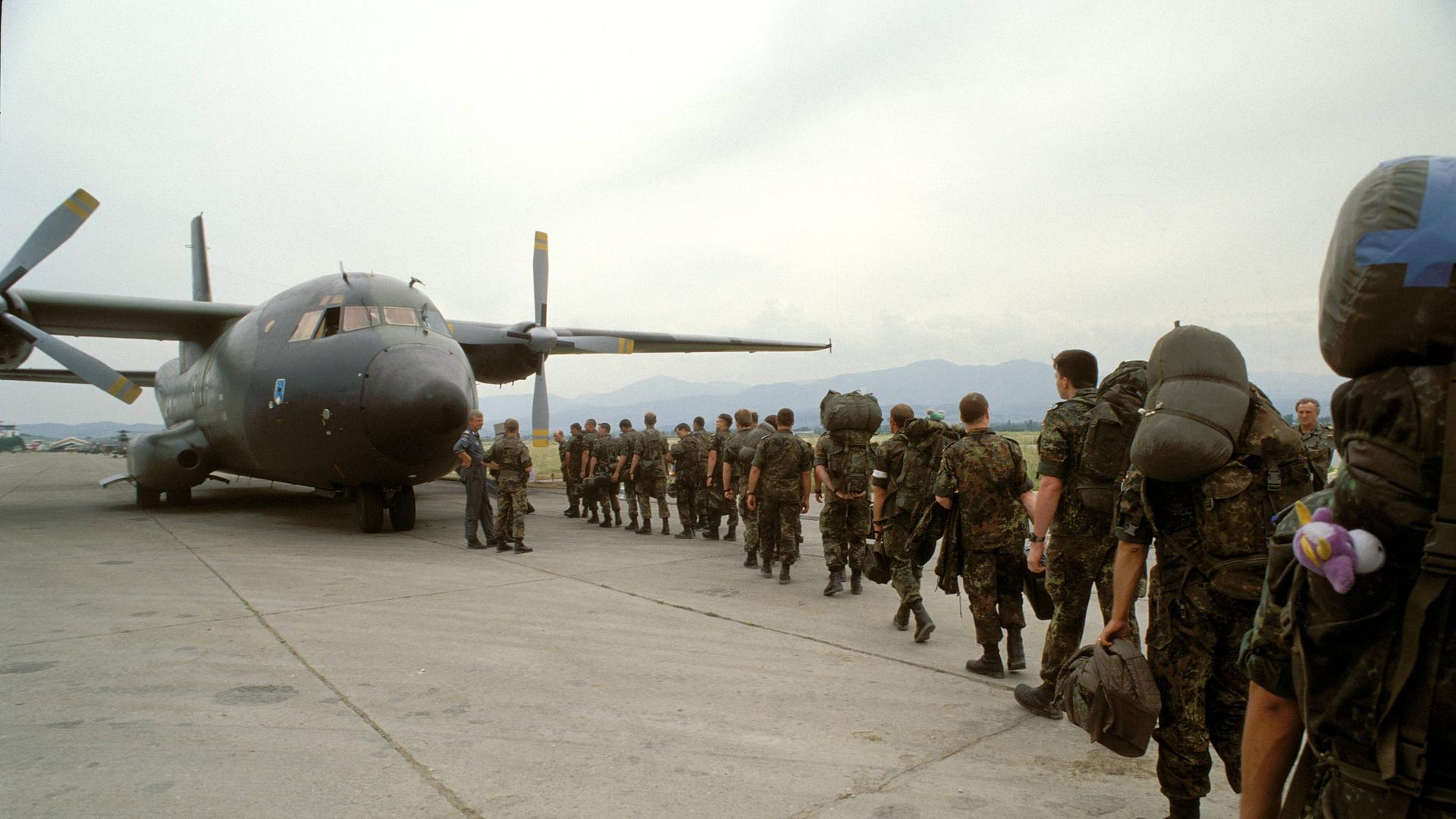 Angehörige der Bundeswehr steigen während des Einsatzes im Grenzgebiet Kosovo - Mazedonien Ende der 1990er Jahre in ein Transportflugzeug.