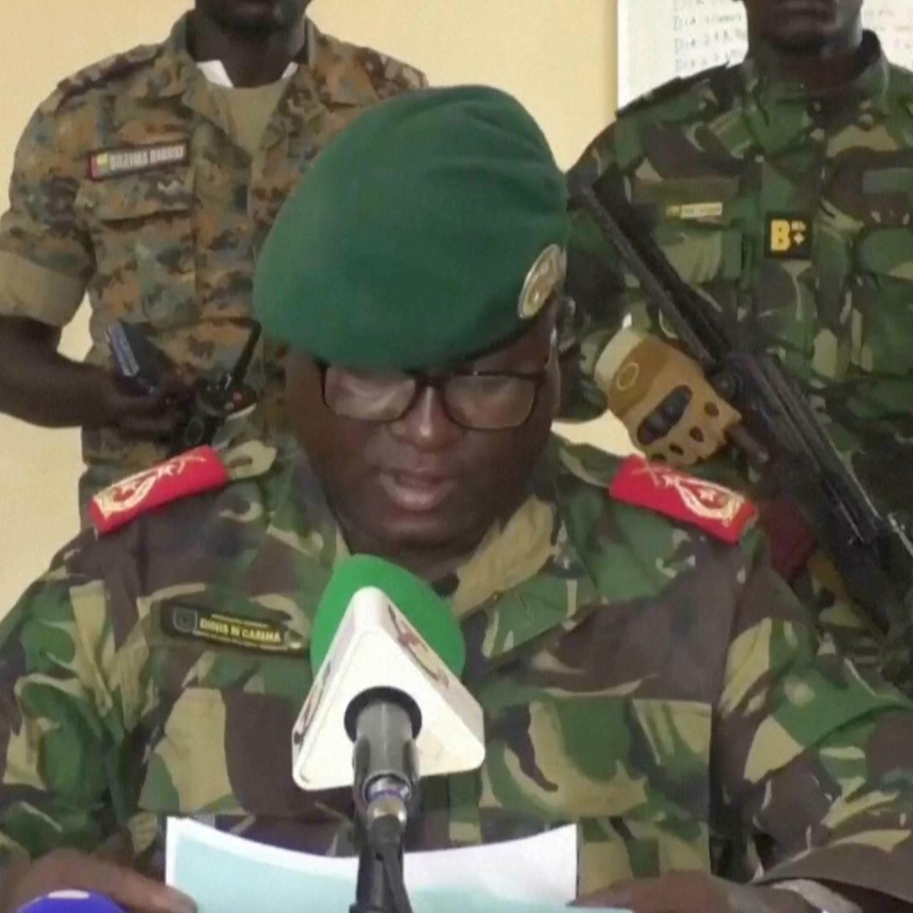 Dinis N'Tchama, Sprecher des Militärs, verliest eine Erklärung. Um ihn herum sind mehrere Soldaten. 