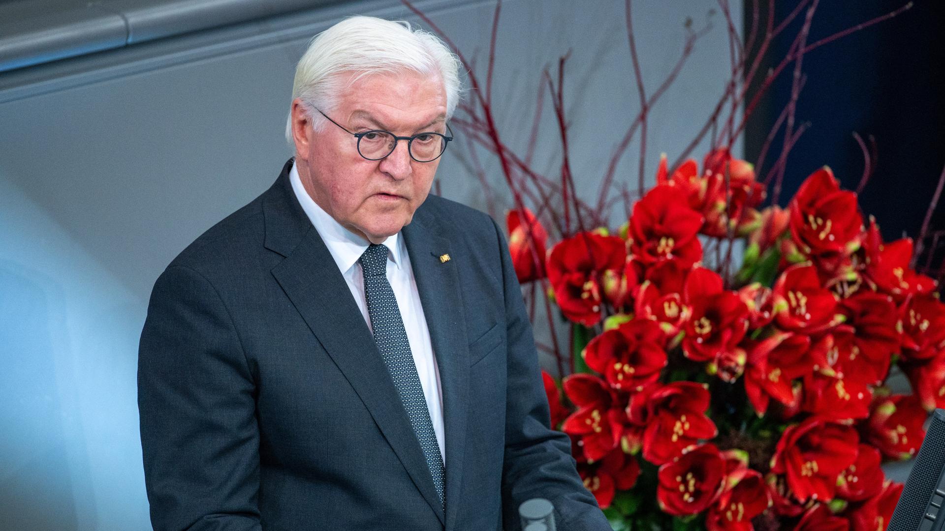 Bundespräsident Frank-Walter Steinmeier steht am Rednerpult im Bundestag und spricht. Neben ihm steht ein großer Strauß roter Blumen.