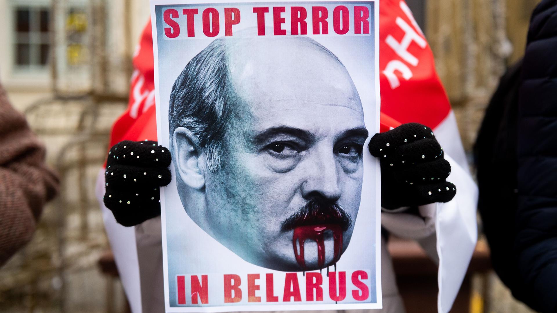 Ein Teilnehmer einer Demonstration gegen den belarussischen Machthaber Alexander Lukaschenko in Polen hält ein Plakat in der Hand auf dem steht "Stop Terror in Belarus"