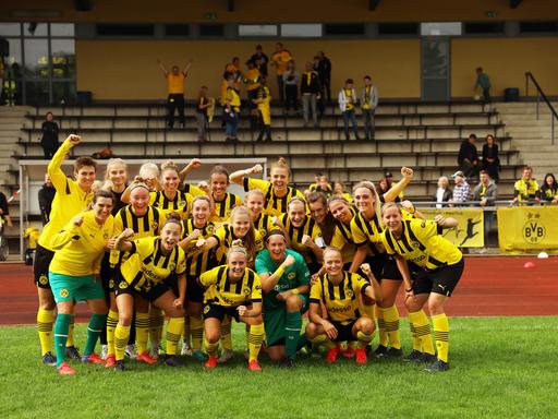 Die Frauen-Fußballmannschaft des BVB jubelt und lacht in die Kamera