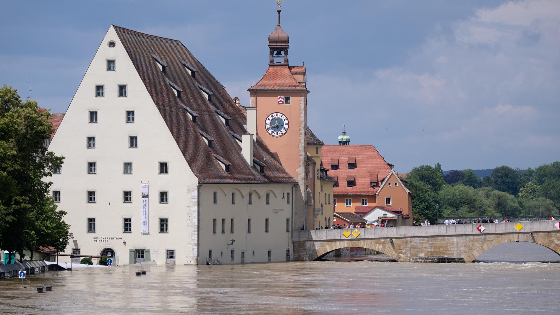 Bayern, Regensburg: Menschen stehen in der Altstadt auf der Steinernen Brücke und schauen sich das Hochwasser an. Seit Tagen kämpfen die Helfer in Bayern gegen die Flut und ihre Folgen.