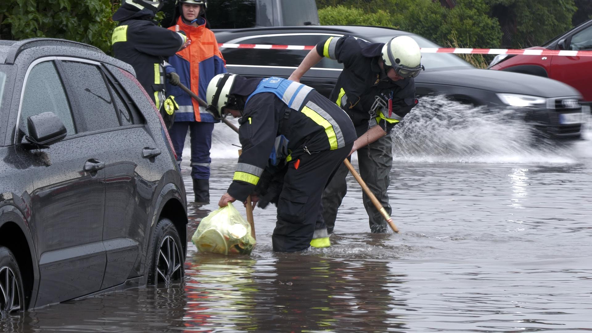 Feuerwehrleute öffnen in Nürnberg Gullys auf einer unter Wasser stehenden Straße. Heftige Regenfälle haben in Teilen Bayerns Straßen überflutet und Keller unter Wasser gesetzt. 