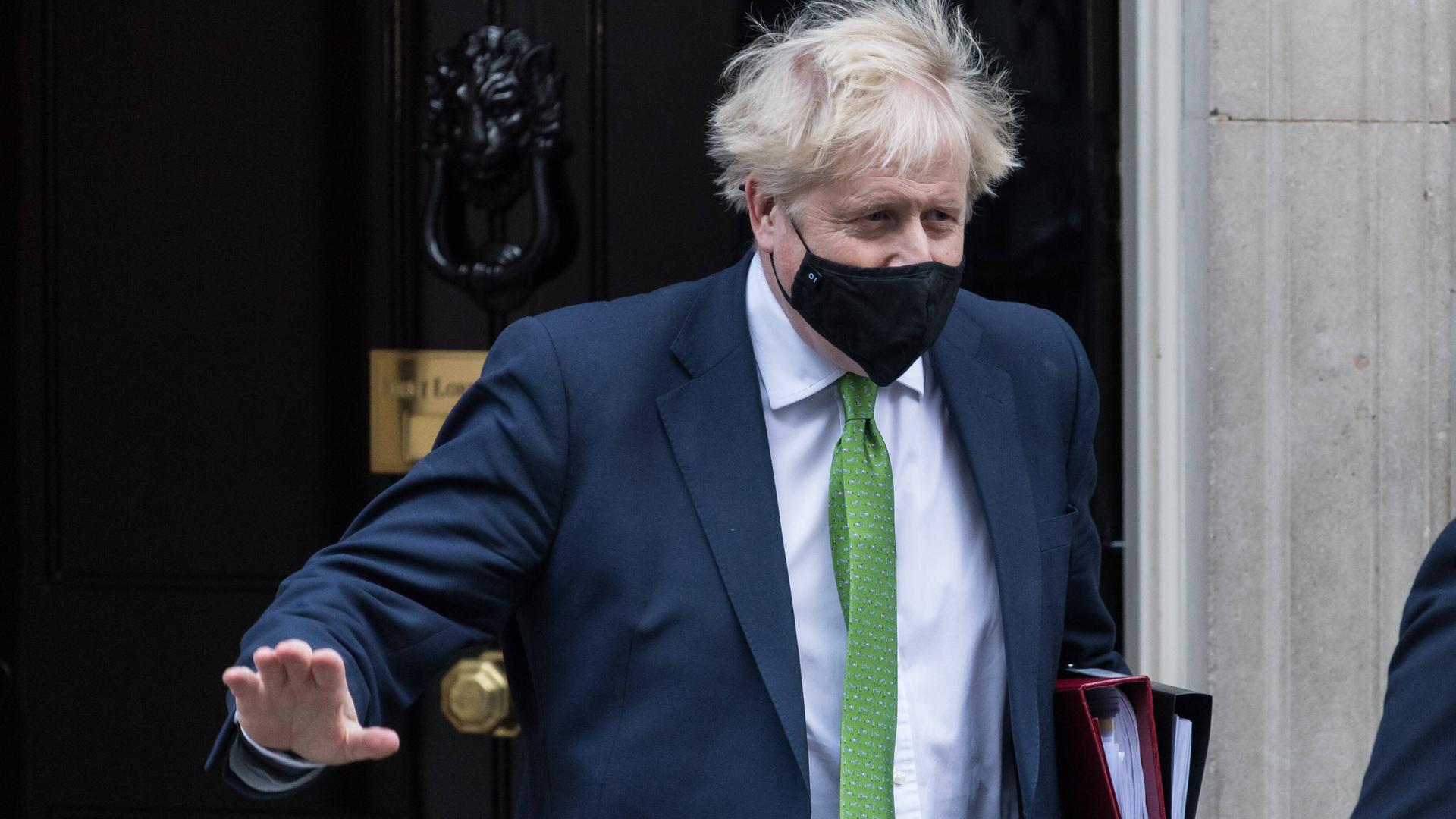 Boris Johnson kommt aus einer Haustür heraus.
