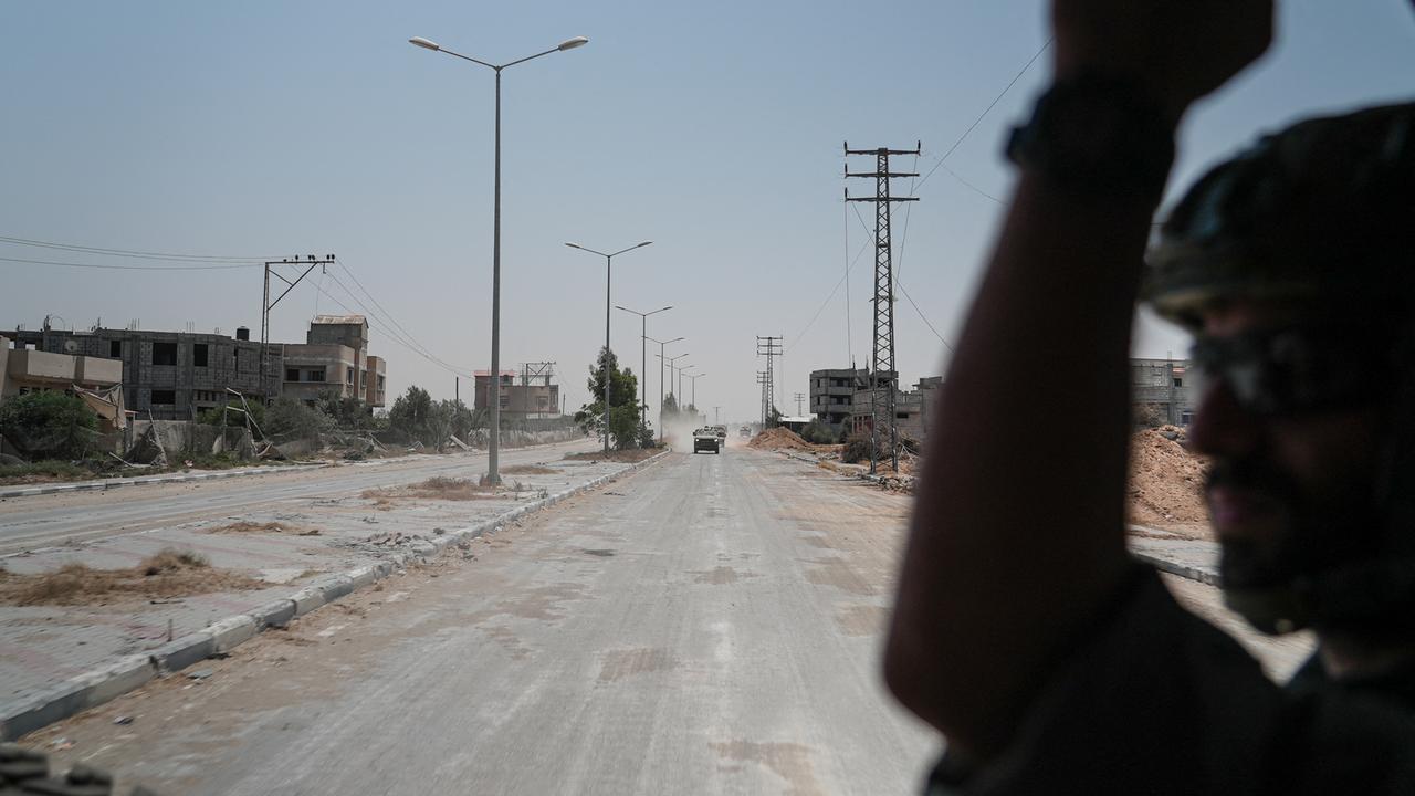 Ein israelischer Soldat auf der Ladefläche eines Trucks in Gaza, im Hintergrund teils zerstörte Gebäude