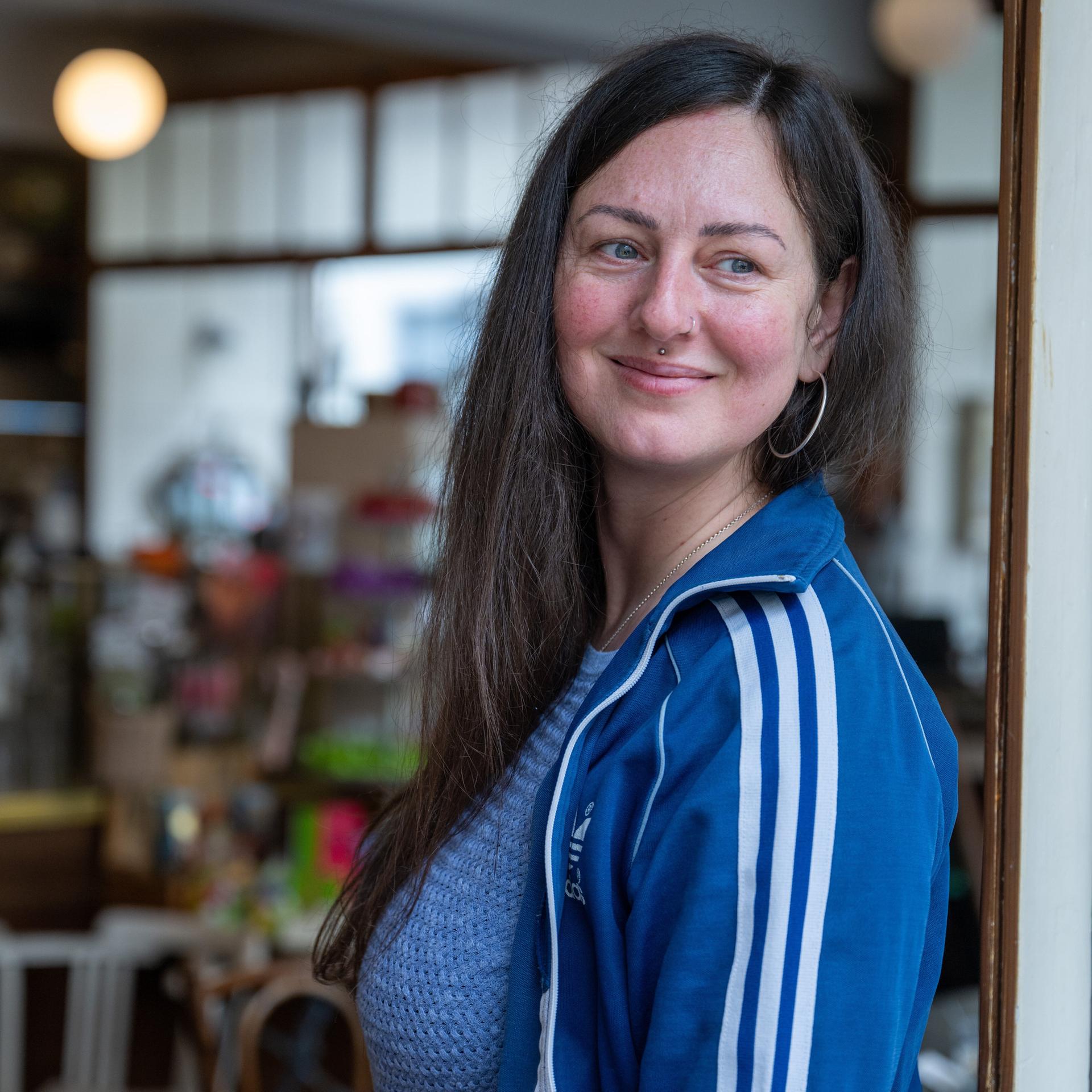 Nina Fuchs steht in einem Türrahmen, schaut zur Seite und lächelt. 