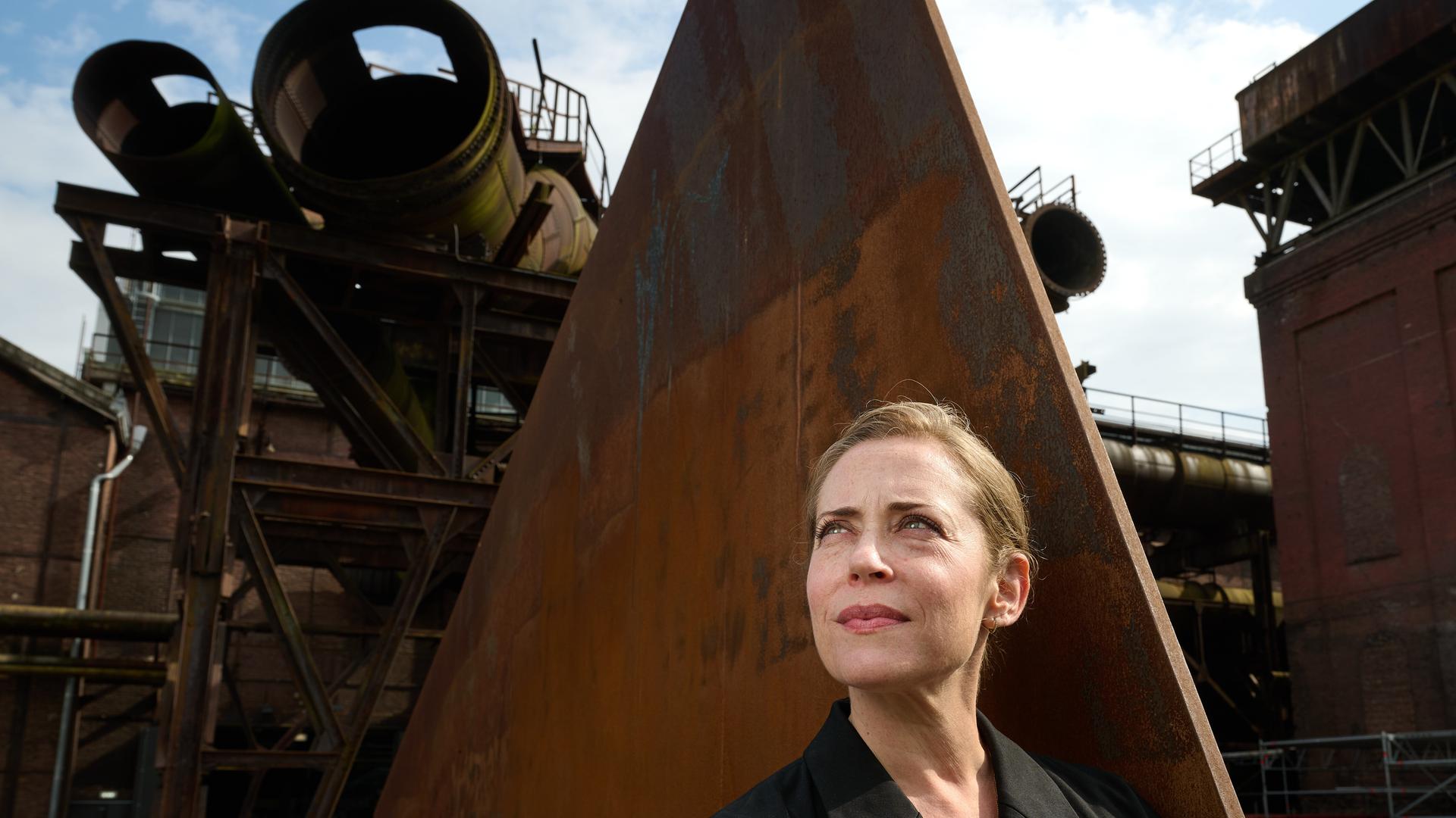 Lydia Steier, Intendantin der Ruhrtriennale ab 2027, steht in der Jahrhunderthalle vor einer Eisenskulptur Lydia Steier, Intendantin der Ruhrtriennale ab 2027, steht in der Jahrhunderthalle vor einer Eisenskulptur