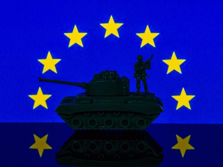 Eine Panzerattrappe steht unter dem Sternenrund der EU-Flagge