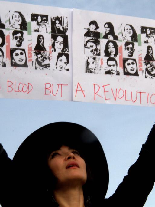 Die Schauspielerin Mitra Farahani protestiert beim Gijón International Film Festival. Sie saß selbst einige Wochen im Iran im Gefängnis, lebt aber inzwischen in Frankreich. Sie hält ein Schild mit Bildern von Opfern der Repression in die Luft. 