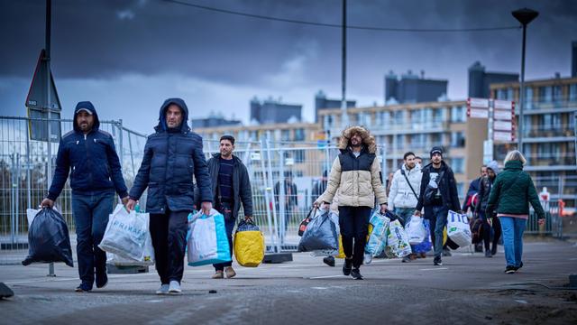 Männer laufen mit Taschen in der Hand einen Weg entlang. Sie hoffen auf Asyl in den Nieder-Landen.