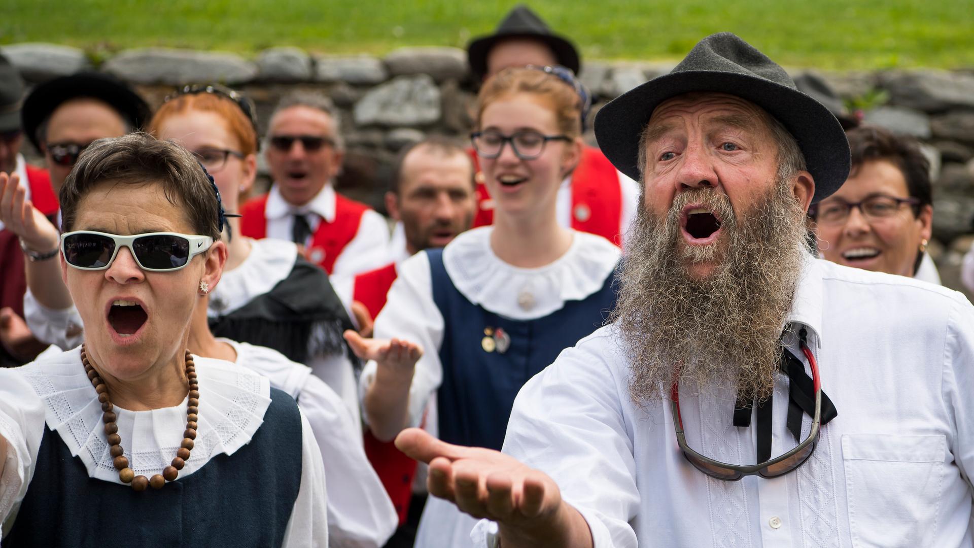 Eine Gruppe von Männern und Frauen in Tracht jodelt