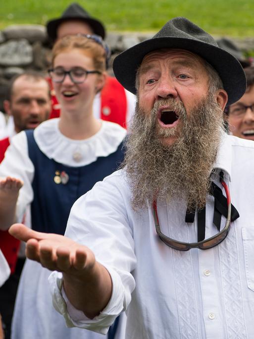 Eine Gruppe von Männern und Frauen in Tracht jodelt