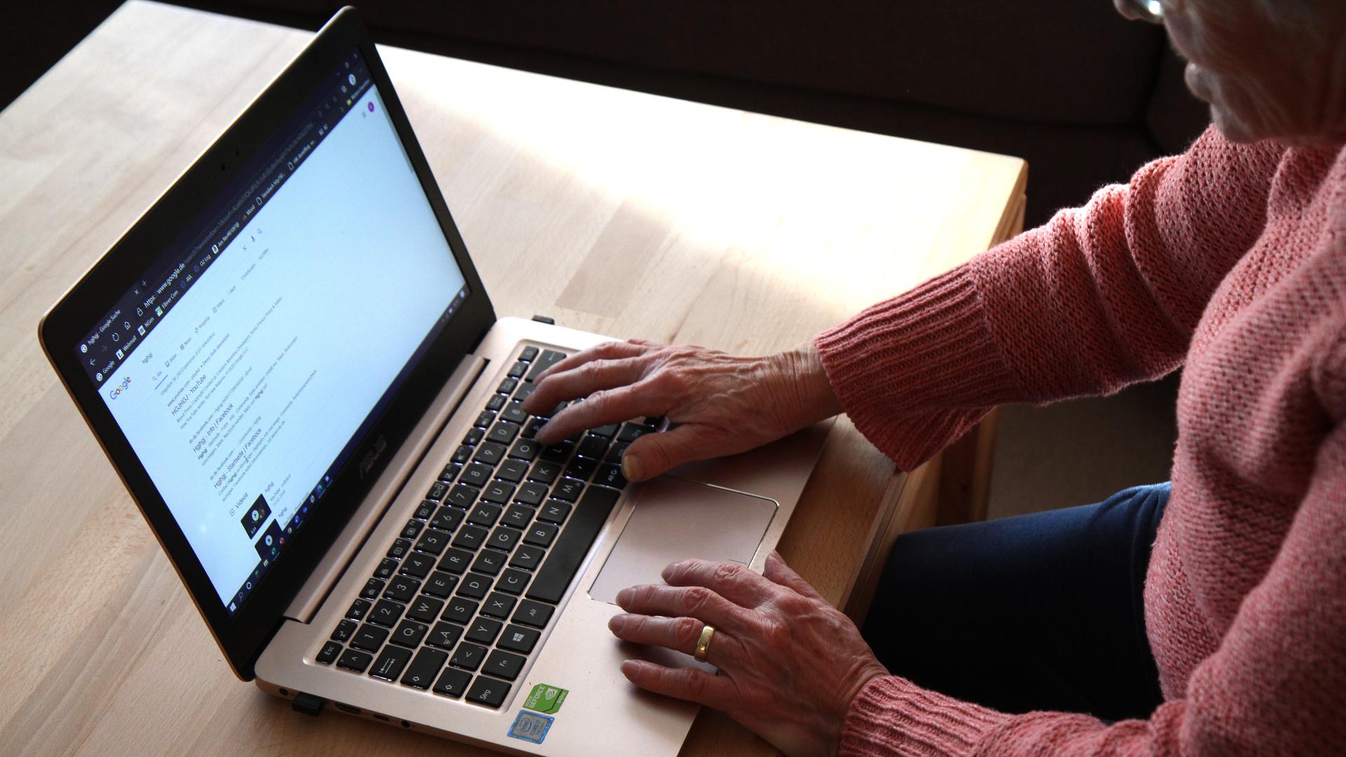 Eine Frau sitzt vor einem Laptop und nutzt eine Suchmaschine