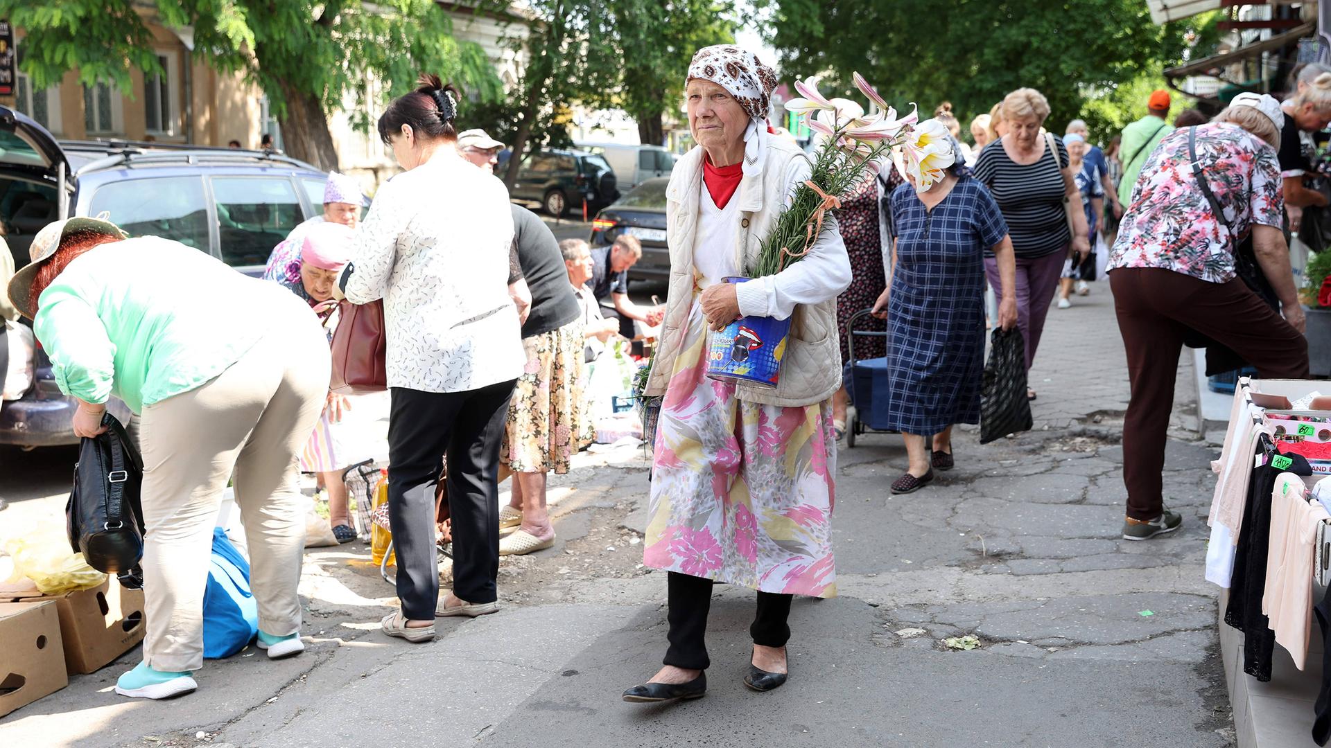Frauen beim Einkaufen mit Blumen in der Hand. Alltag in Chisinau, der Hauptstadt von Moldau, 2023.