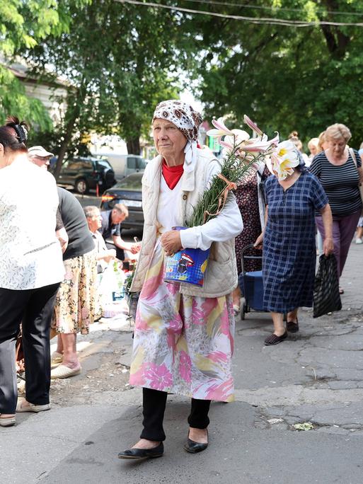 Frauen beim Einkaufen mit Blumen in der Hand. Alltag in Chisinau, der Hauptstadt von Moldau, 2023.