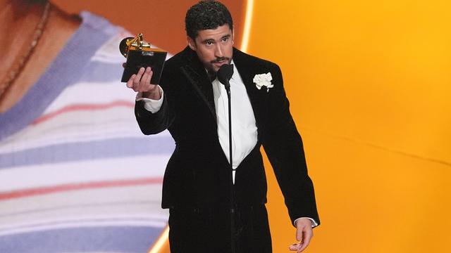 Bad Bunny hält seinen Grammy-Preis in der Hand. Er spricht in ein Mikrofon.