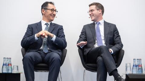 Die Spitzenkandidaten zur Landtagswahl in Baden-Württemberg, Manuel Hagel (CDU, r) und Cem Özdemir (Bündnis 90/Die Grünen) sitzen bei einer Veranstaltung zusammen und blicken sich an. 