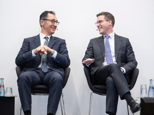 Die Spitzenkandidaten zur Landtagswahl in Baden-Württemberg, Manuel Hagel (CDU, r) und Cem Özdemir (Bündnis 90/Die Grünen) sitzen bei einer Veranstaltung zusammen und blicken sich an. 