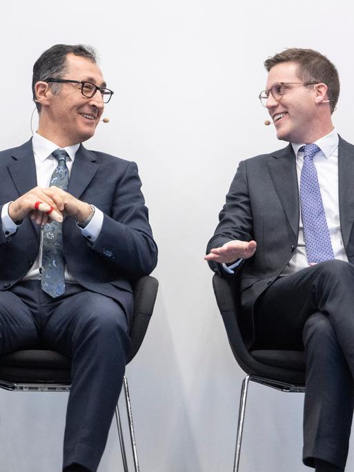 Die Spitzenkandidaten zur Landtagswahl in Baden-Württemberg, Manuel Hagel (CDU, r) und Cem Özdemir (Bündnis 90/Die Grünen) sitzen bei einer Veranstaltung zusammen und blicken sich an. 