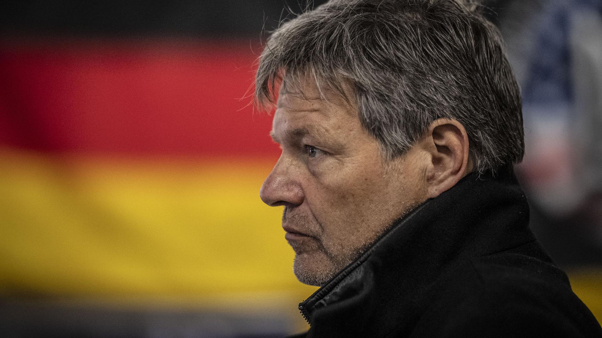 Robert Habeck im Profil, im Hintergrund ist die deutsche Flagge zu sehen.