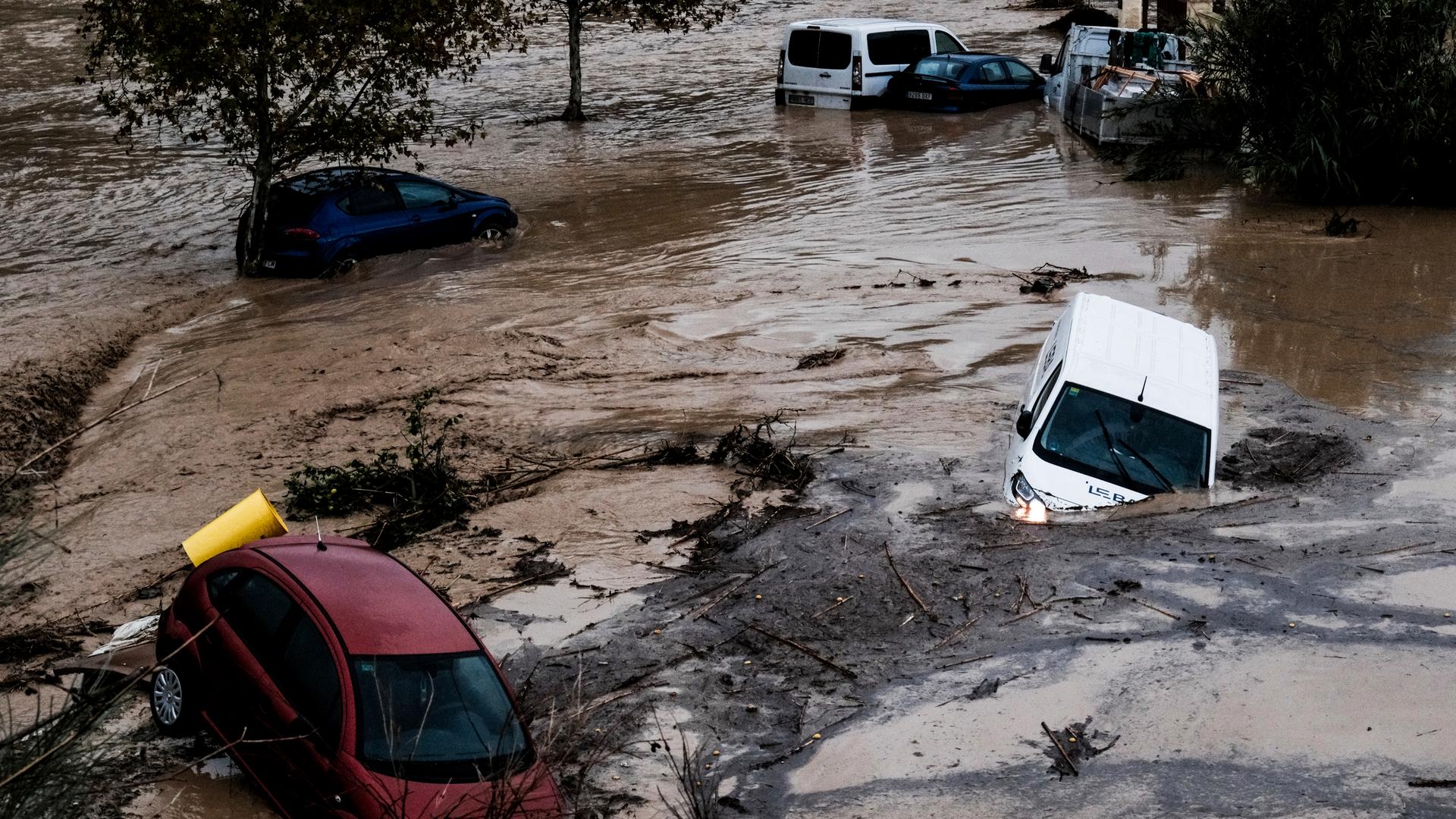 Das Foto zeigt eine überflutete Straße. Autos werden vom Wasser weggeschwemmt.