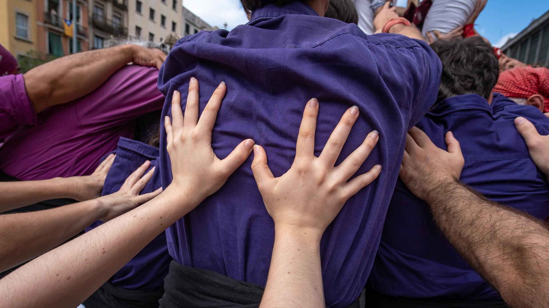 Hände stützen die Rücken von vor ihnen stehenden Menschen