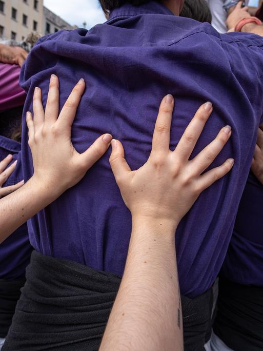 Hände stützen die Rücken von vor ihnen stehenden Menschen