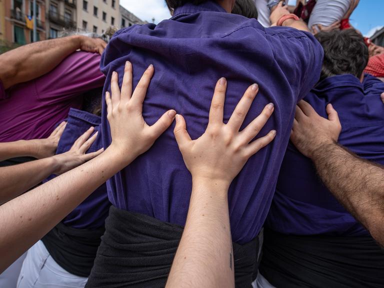 Hände stützen die Rücken von vor ihnen stehenden Menschen