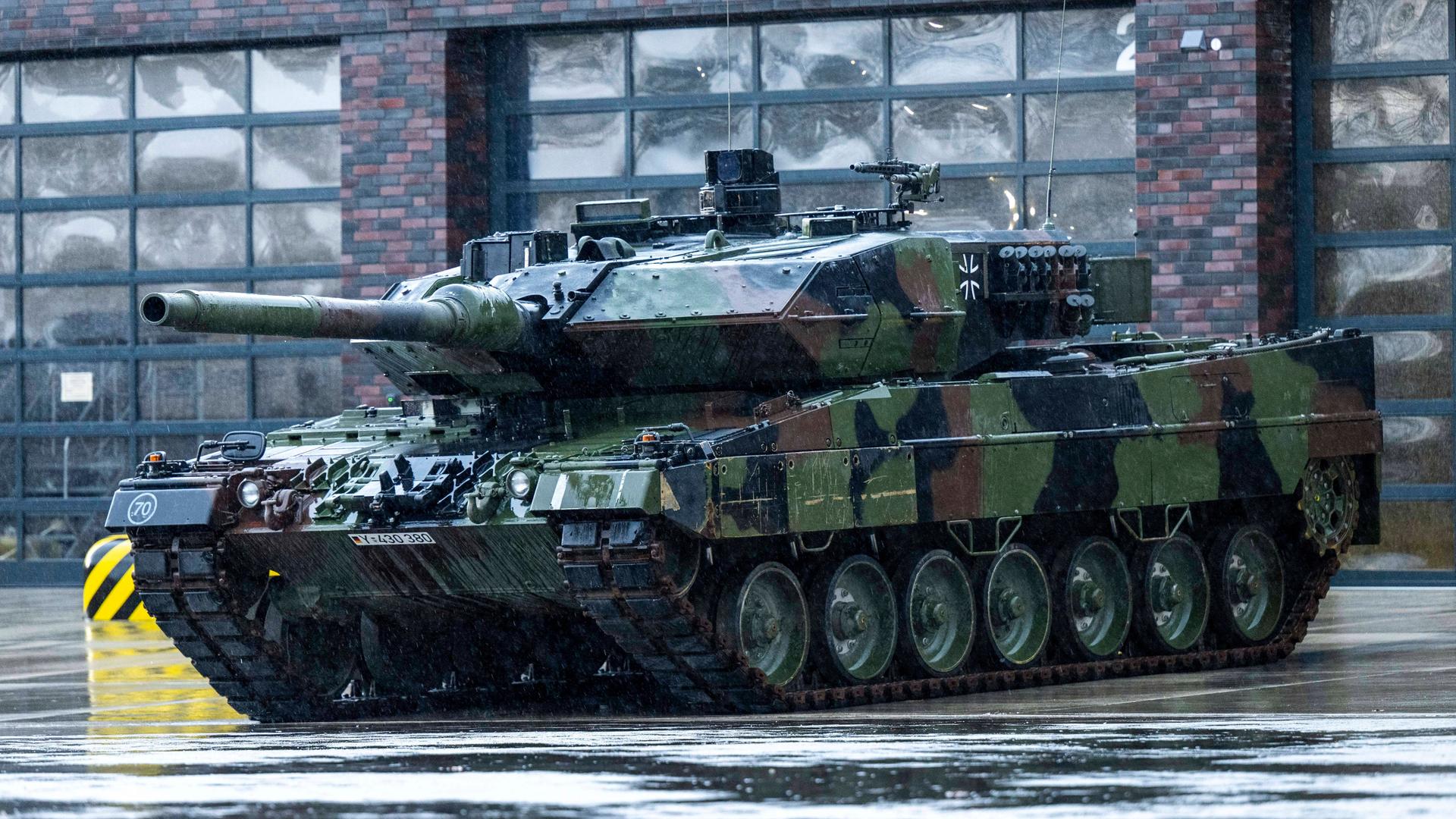 Vor einer Garagenhalle steht ein Leopard 2 Panzer der Bundeswehr.