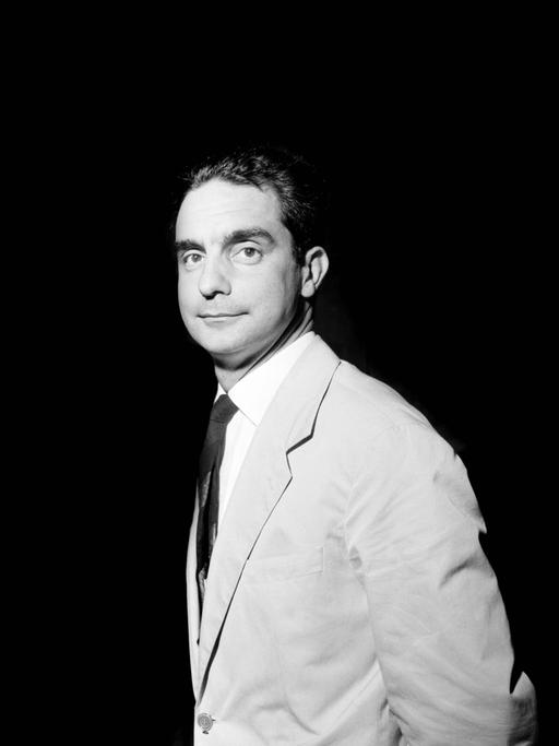 Porträtaufnahme des Schriftstellers Italo Calvino: Er steht hell ausgeleuchtet vor einen schwarzen Hintergrund.