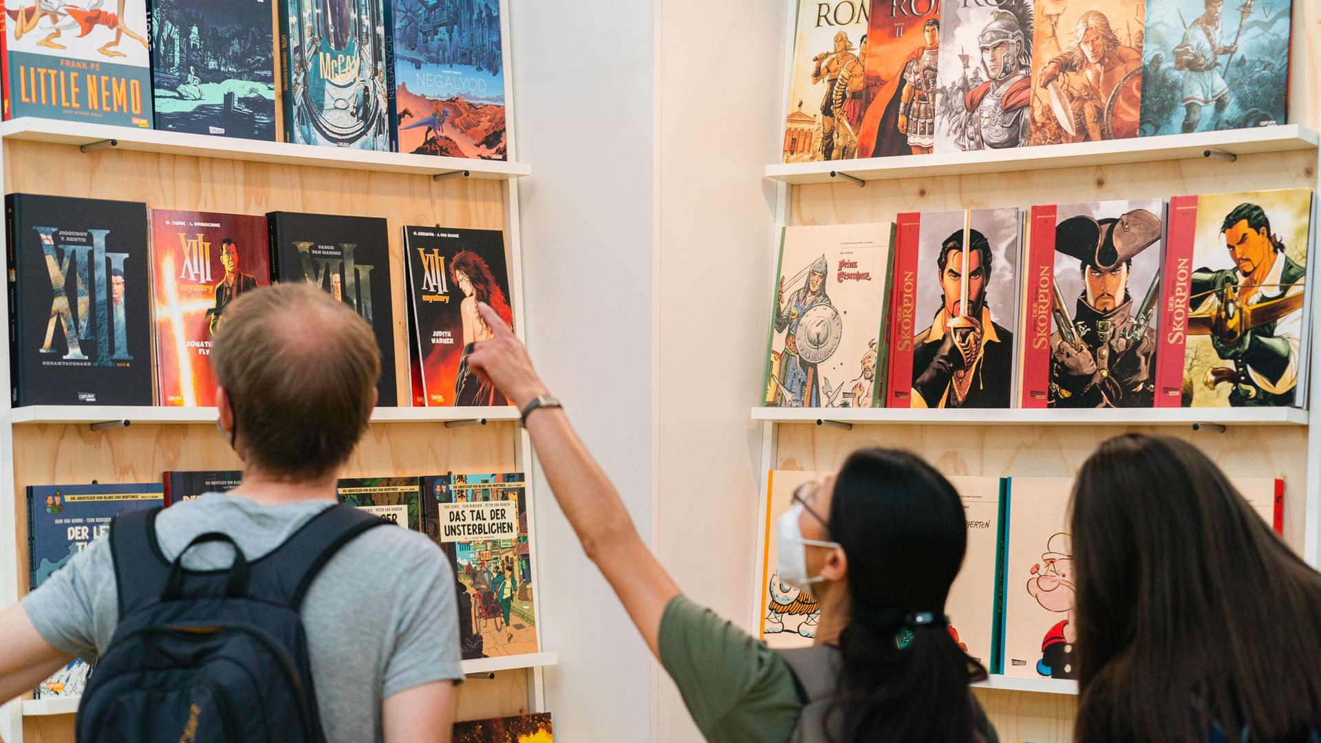 Besucher betrachten Comics in einer Halle auf dem Comic-Salon 2022 in Erlangen.