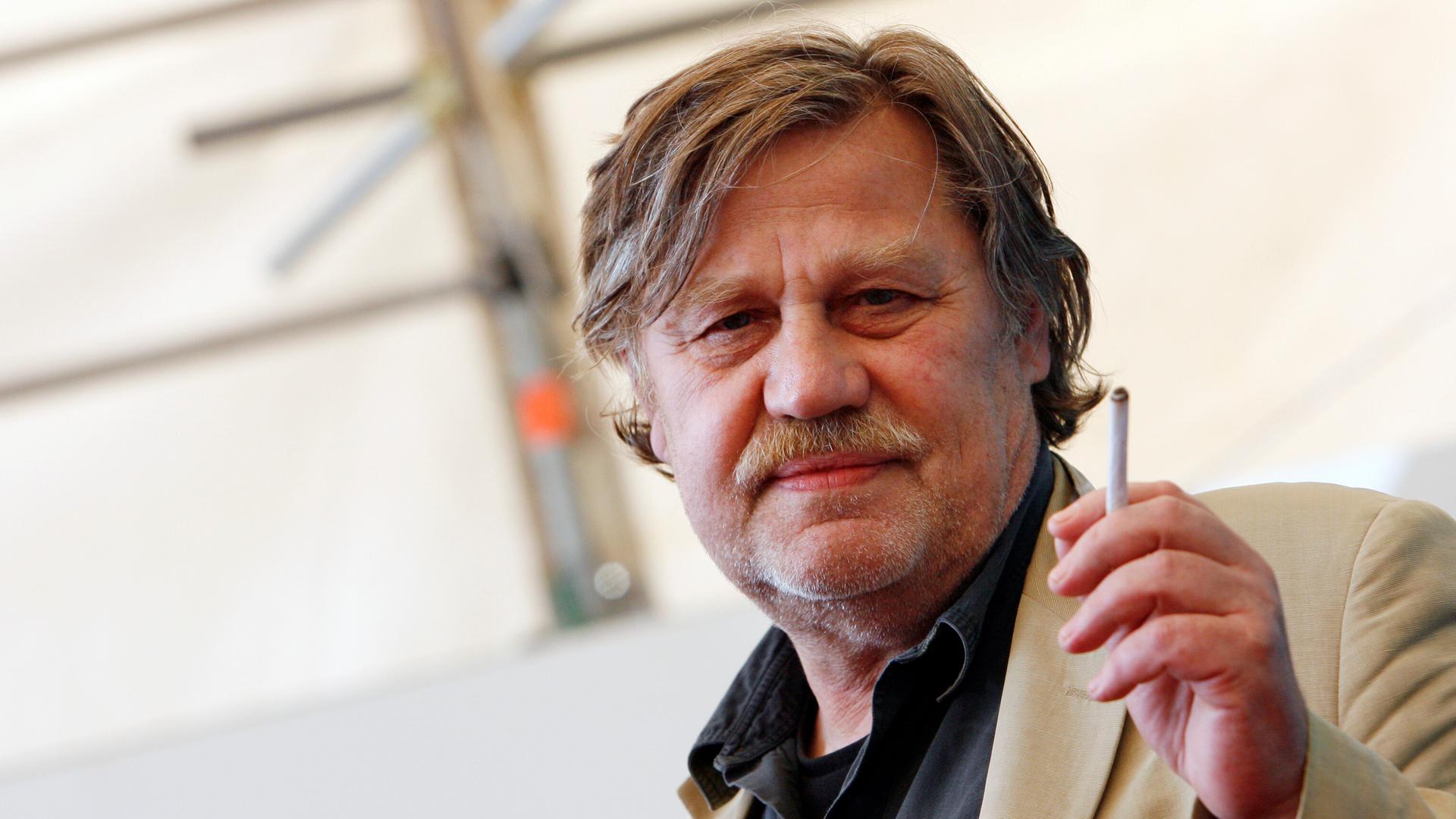 Hartmut Bitomsky in einem hellen Sakko mit einer Zigarette in der Hand