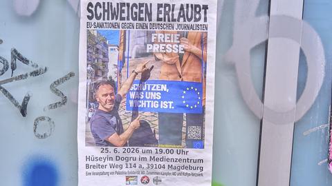 An einer Wand hängt ein Plakat mit der Aufschrift "Schweigen erlaubt - EU-Sanktionen gegen einen deutschen Journalisten".