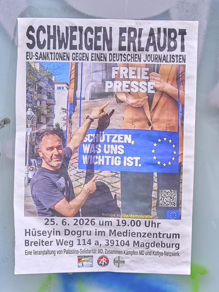 An einer Wand hängt ein Plakat mit der Aufschrift "Schweigen erlaubt - EU-Sanktionen gegen einen deutschen Journalisten".
