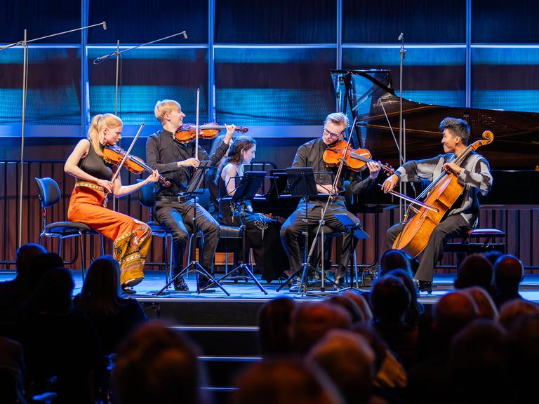 Die jungen Musiker sitzen mit ihren Instrumenten gut gelaunt im Spiel auf der Bühne des Kammermusiksaals im Deutschlandfunk Kultur.