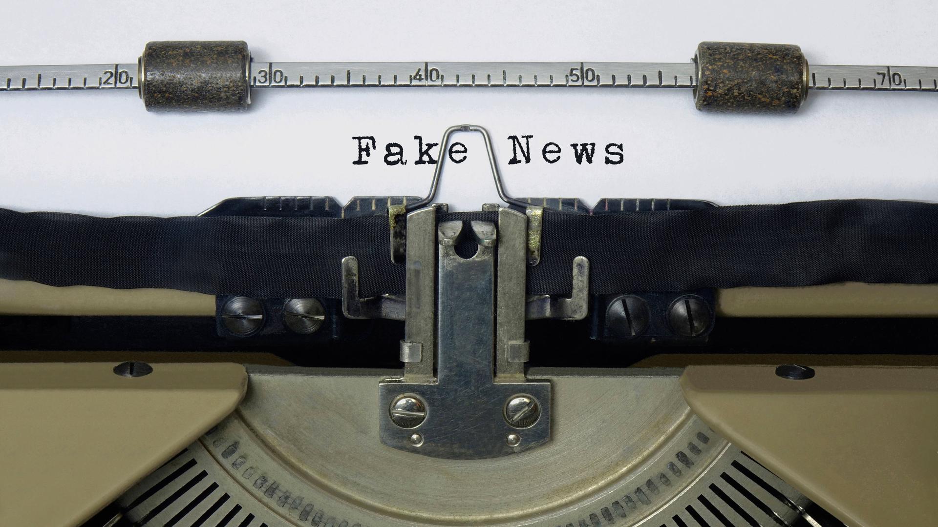 Auf dem Papier einer alten Schreibmaschine steht der Schriftzug Fake News.
