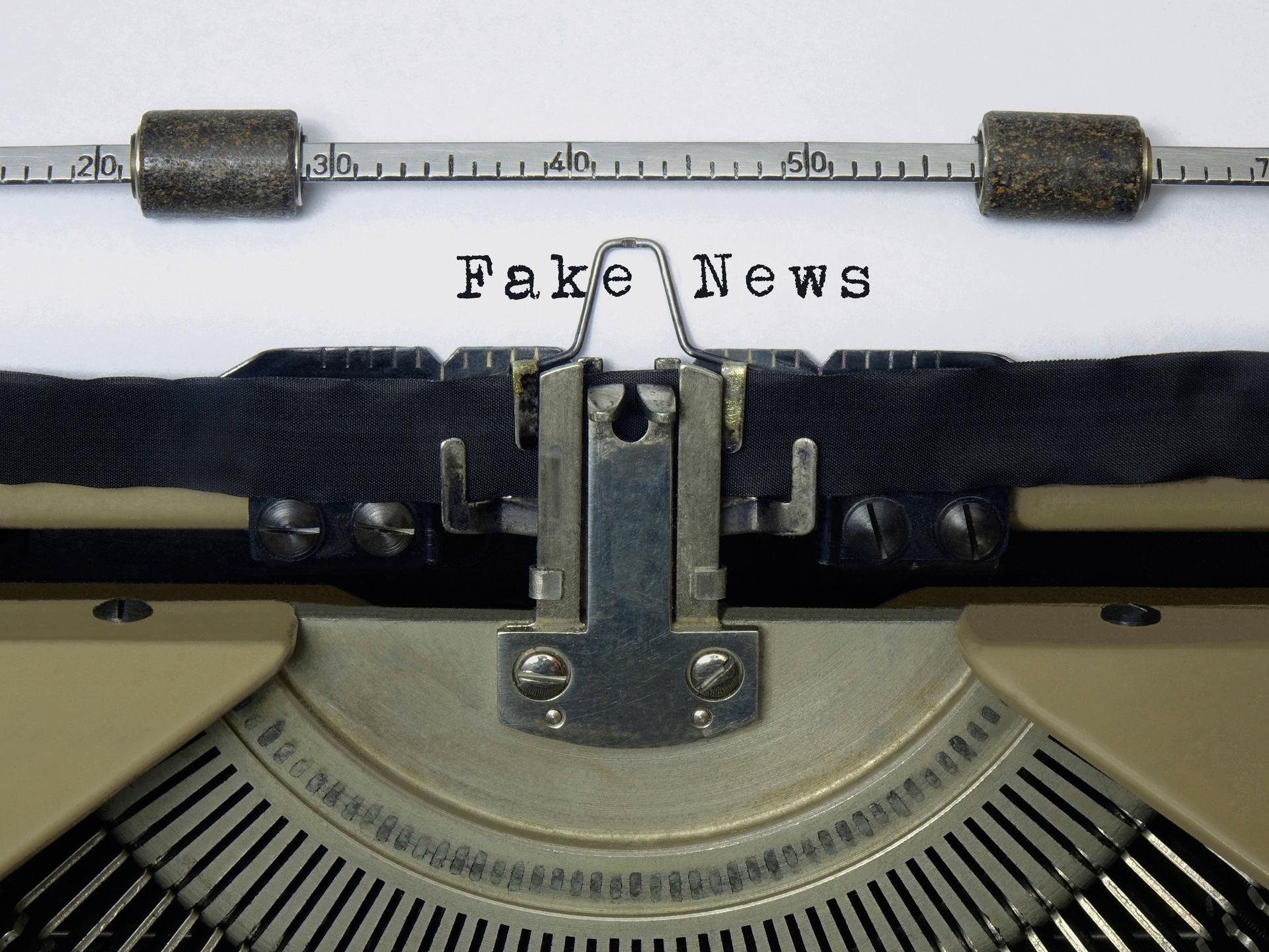 Auf dem Papier einer alten Schreibmaschine steht der Schriftzug Fake News.
