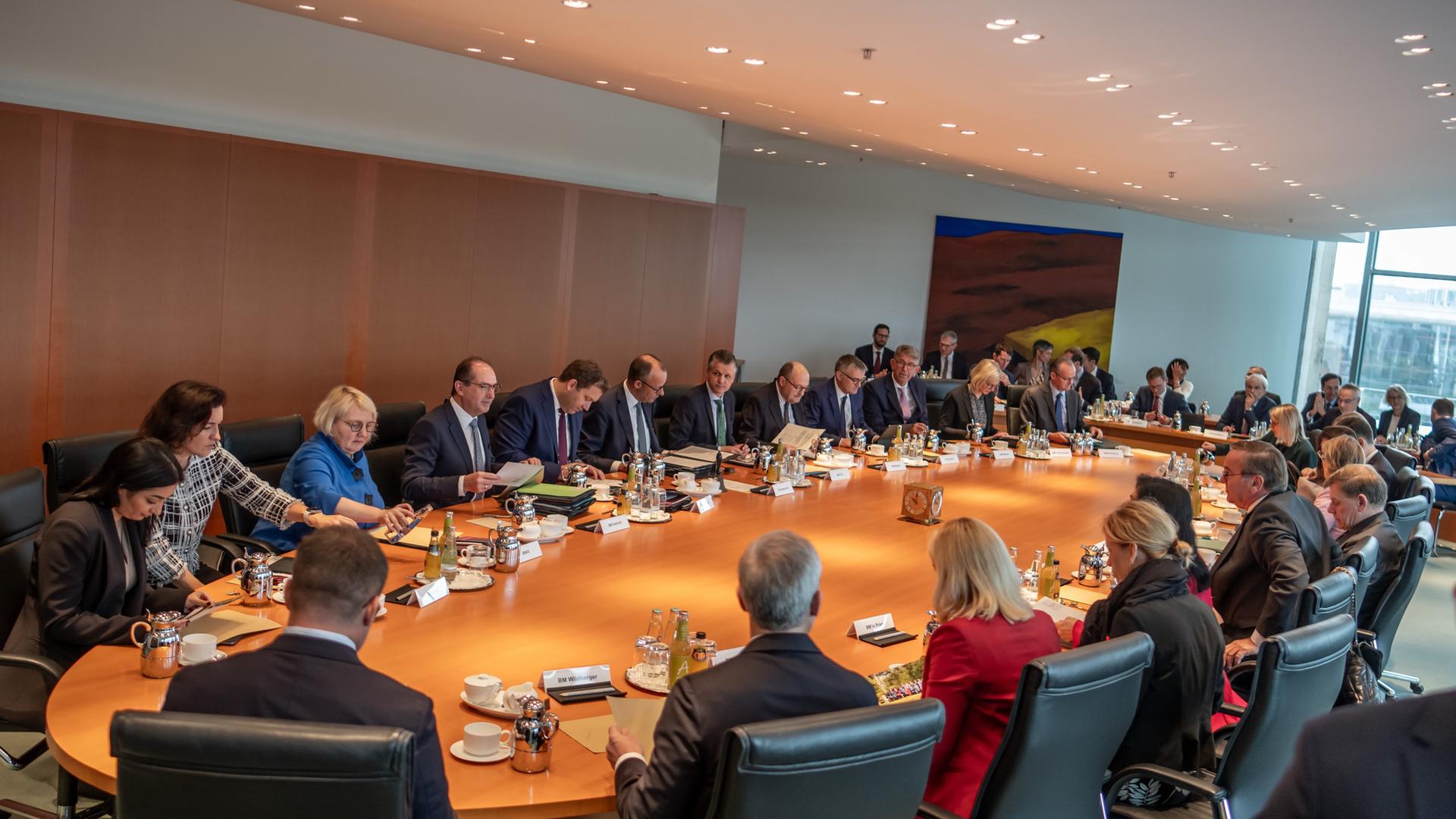 Die Ministerinnenund Minister sowie Bundeskanzler Merz sitzen an dem bräunlichen ovalen Tisch. 