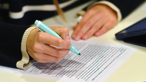 Hände einer Schülerin mit Textmarker und Arbeitsblatt