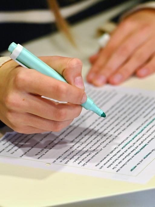Hände einer Schülerin mit Textmarker und Arbeitsblatt