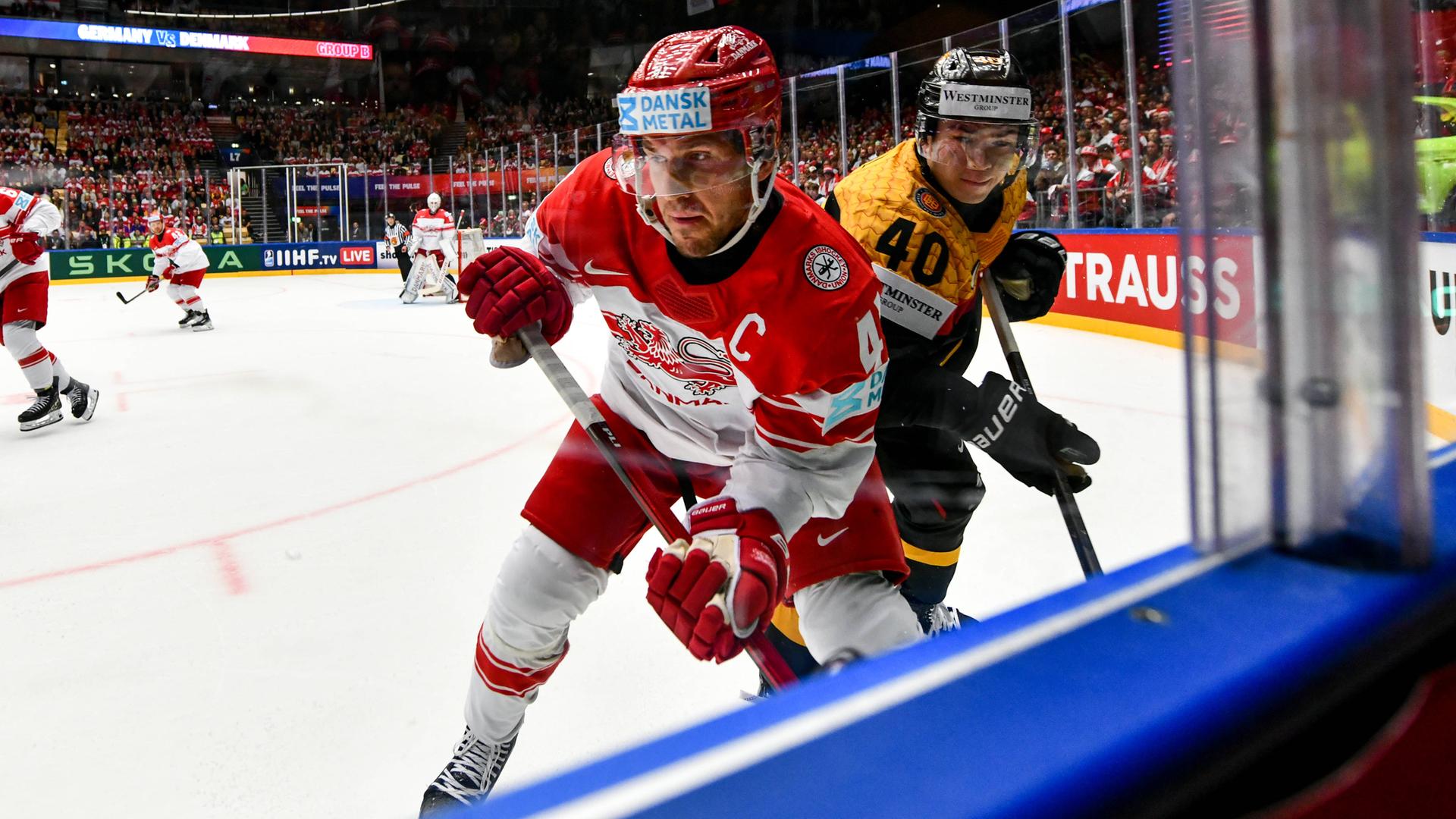 Zwei Eishockey-Spieler vor der Scheibe am Rande des Spielfelds.